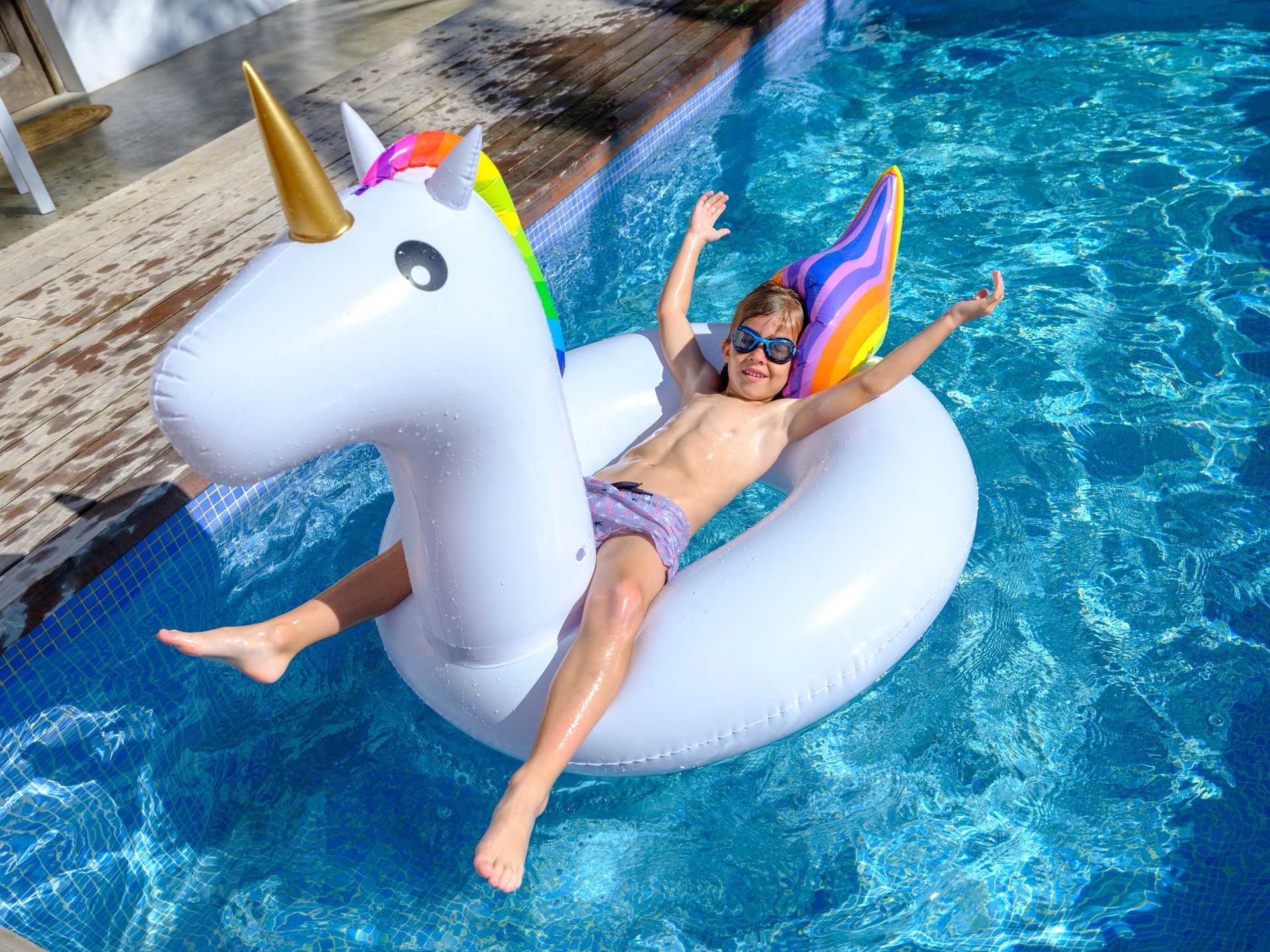 Content kid lying on inflatable ring and floating in swimming po